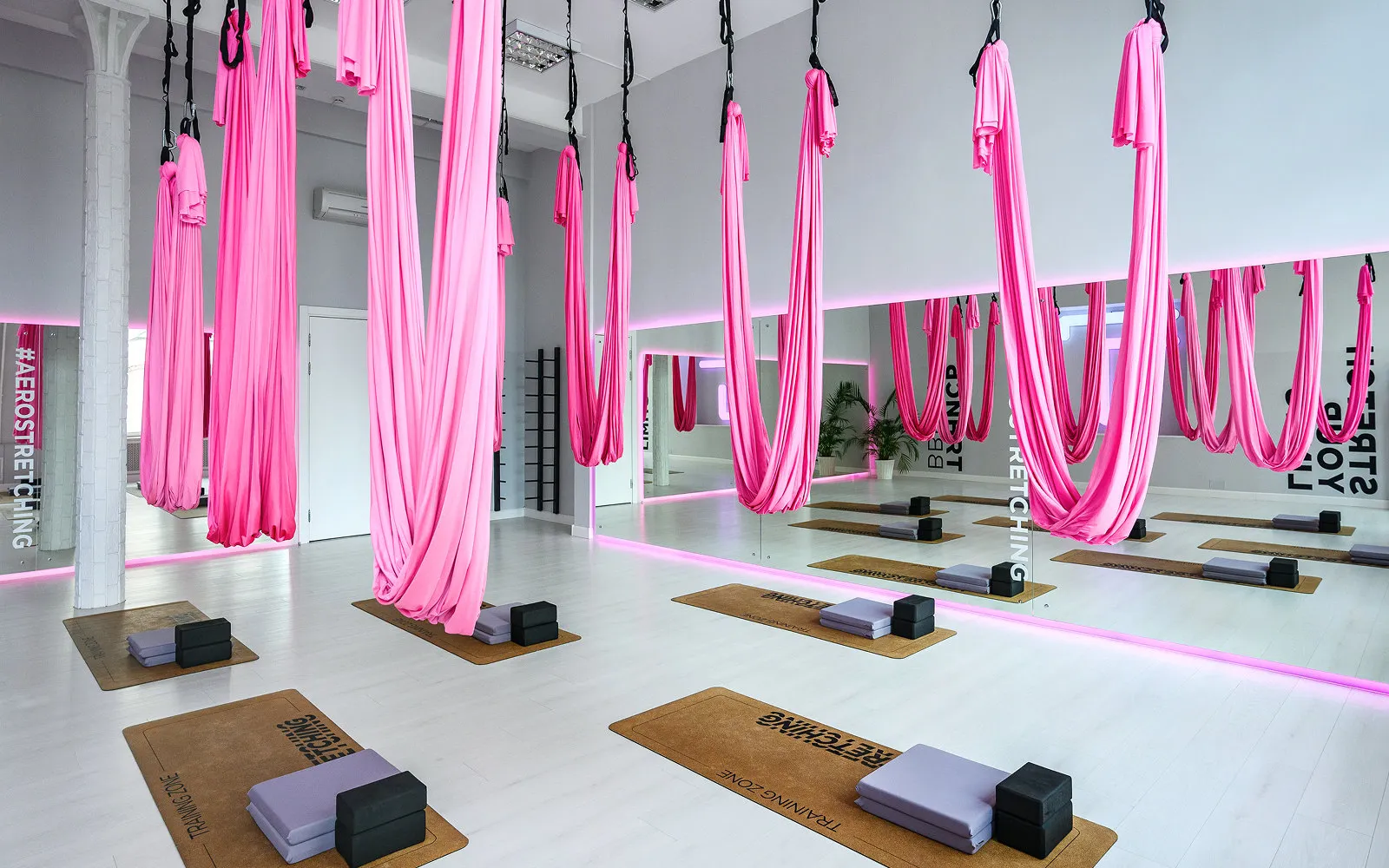 Studio für Aerial Stretching mit pinkfarbenen Tüchern, Matten und Blöcken
